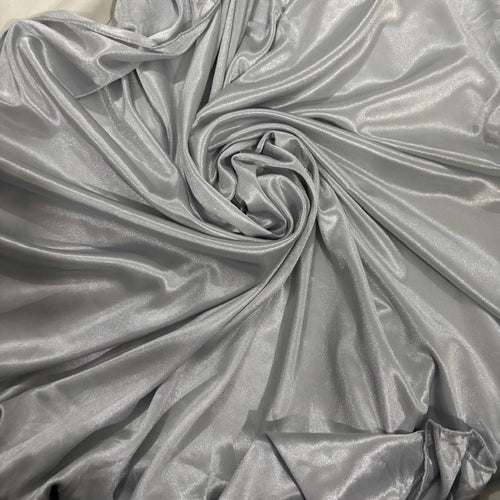 A close-up of shiny silver-gray fabric draped in a spiral pattern, showing its smooth, satin-like texture.